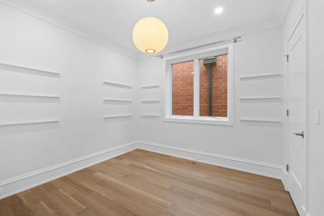 empty room with crown molding and hardwood / wood-style flooring