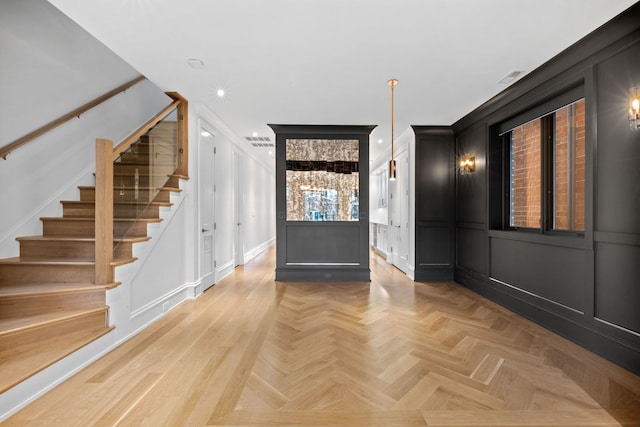 entryway with light parquet floors and ornamental molding