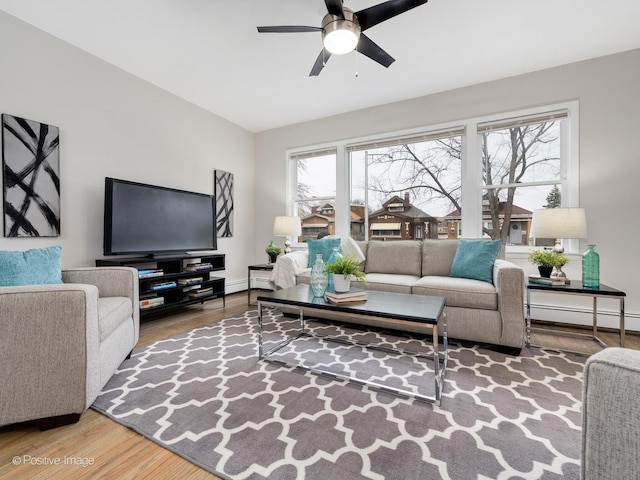 living room featuring wood-type flooring, a baseboard radiator, a wealth of natural light, and ceiling fan