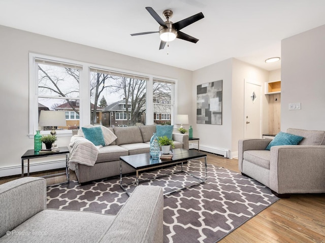 living room featuring hardwood / wood-style flooring, plenty of natural light, ceiling fan, and a baseboard heating unit