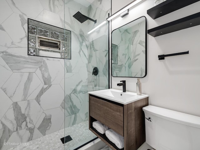 bathroom featuring a tile shower, vanity, and toilet