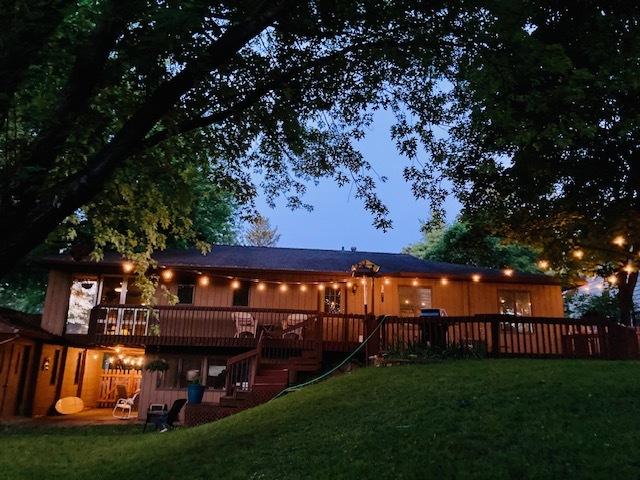 back house at dusk with a lawn and a deck