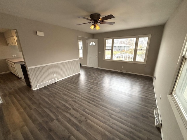 unfurnished living room featuring ceiling fan and dark wood-type flooring