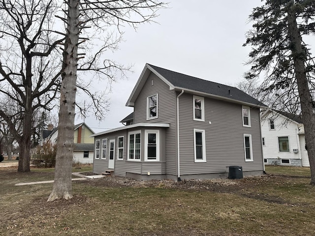 back of house with central air condition unit and a yard