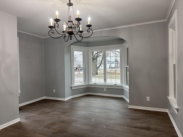 unfurnished dining area featuring dark wood-type flooring, a chandelier, and ornamental molding