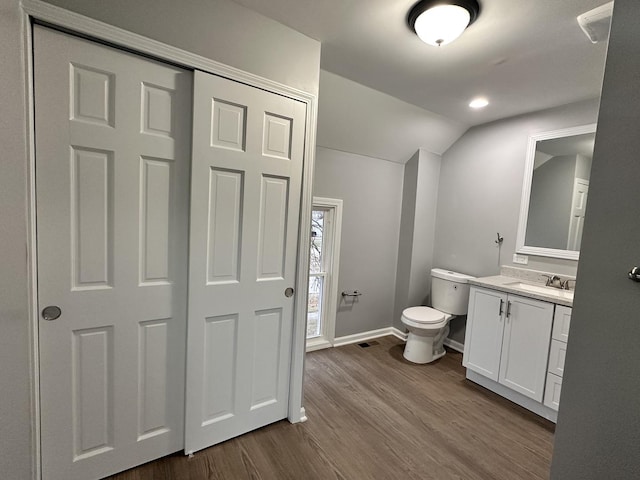 bathroom with vanity, toilet, wood-type flooring, and lofted ceiling