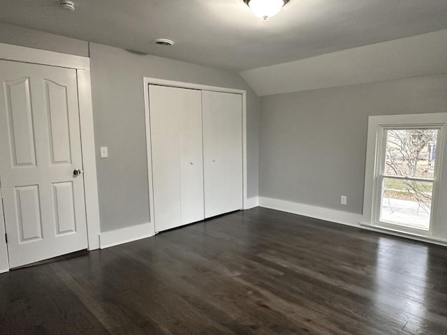 unfurnished bedroom with dark hardwood / wood-style floors, a closet, and lofted ceiling