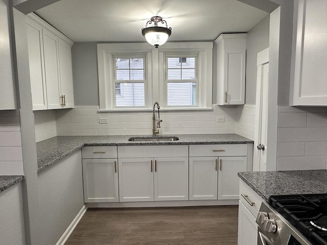 kitchen featuring tasteful backsplash, dark wood-type flooring, sink, dark stone countertops, and white cabinets