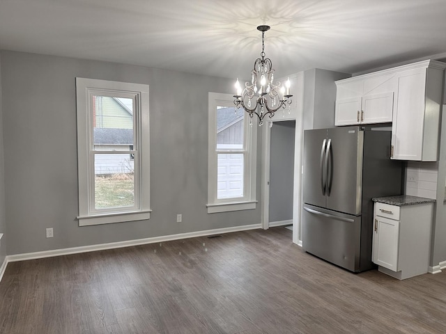 kitchen featuring wood-type flooring, white cabinetry, stainless steel refrigerator, and a chandelier