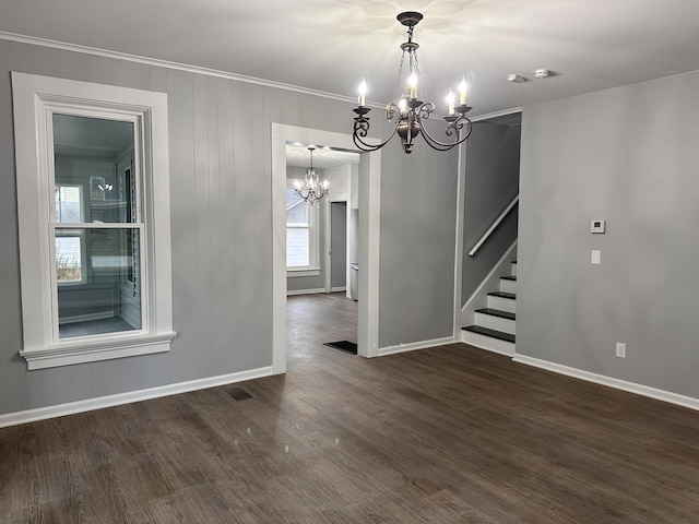 unfurnished dining area featuring crown molding, dark wood-type flooring, and an inviting chandelier