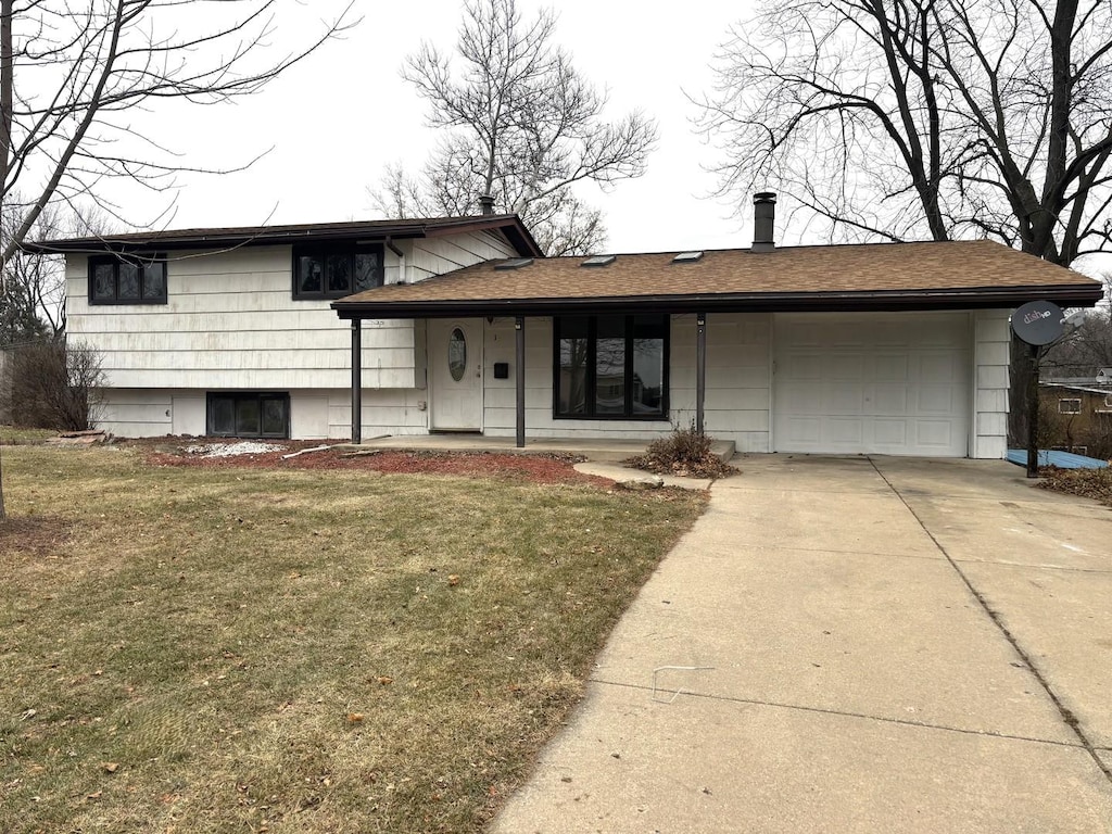 tri-level home with a garage and a front lawn