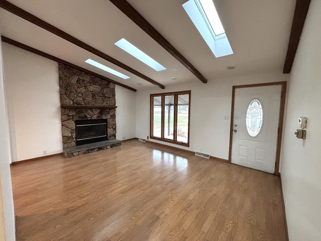 interior space featuring lofted ceiling with beams, a fireplace, and light hardwood / wood-style flooring