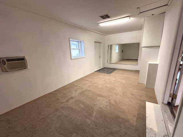 basement with a wall unit AC and light colored carpet