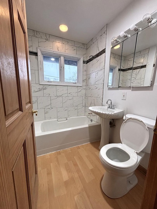 bathroom featuring wood-type flooring, tiled shower / bath combo, and toilet