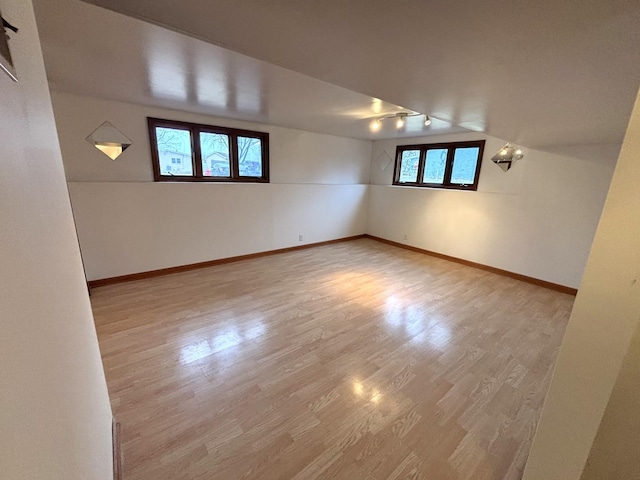 empty room with light hardwood / wood-style floors and vaulted ceiling