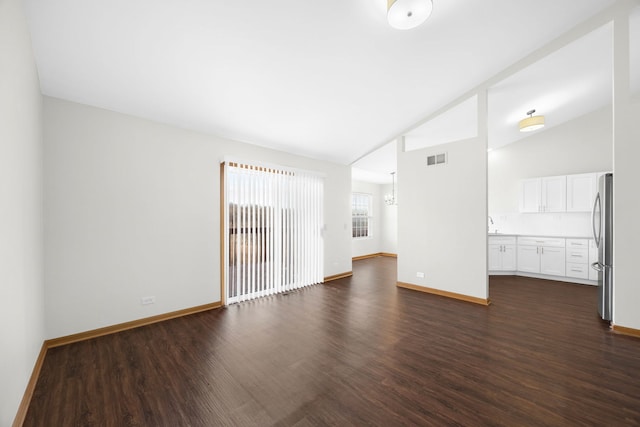 empty room featuring high vaulted ceiling and dark wood-type flooring