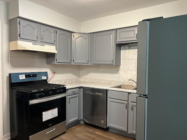 kitchen featuring gray cabinetry, sink, stainless steel appliances, dark hardwood / wood-style flooring, and decorative backsplash