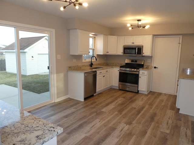 kitchen with white cabinets, a healthy amount of sunlight, a notable chandelier, and appliances with stainless steel finishes