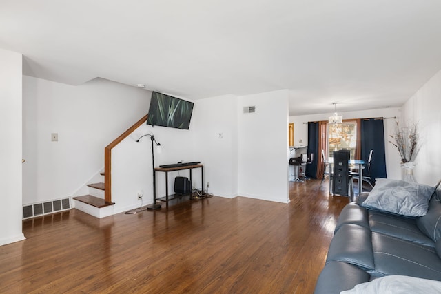 living room with dark hardwood / wood-style floors and an inviting chandelier