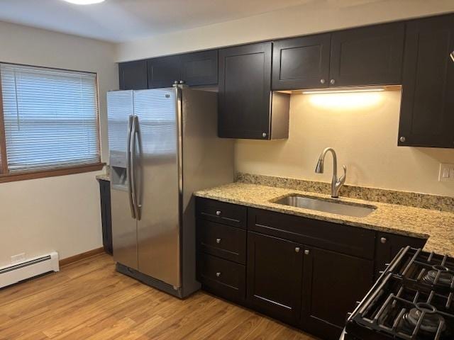 kitchen with light stone countertops, stainless steel fridge with ice dispenser, sink, and light hardwood / wood-style flooring