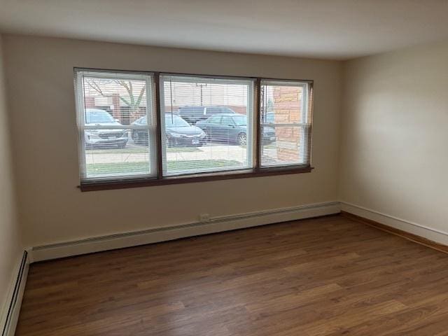 unfurnished room featuring dark hardwood / wood-style floors, a wealth of natural light, and a baseboard radiator