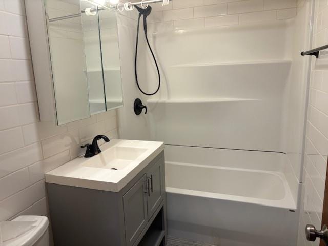 full bathroom with vanity, toilet, shower / tub combination, and tile walls