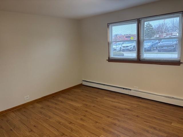 unfurnished room featuring baseboard heating and hardwood / wood-style flooring