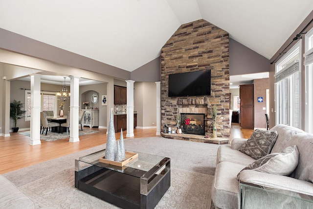 living room with a fireplace, high vaulted ceiling, light hardwood / wood-style flooring, and a notable chandelier