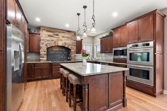 kitchen featuring a breakfast bar, stainless steel appliances, light hardwood / wood-style flooring, a center island, and hanging light fixtures