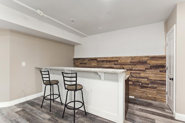 kitchen with a kitchen bar, kitchen peninsula, and dark wood-type flooring