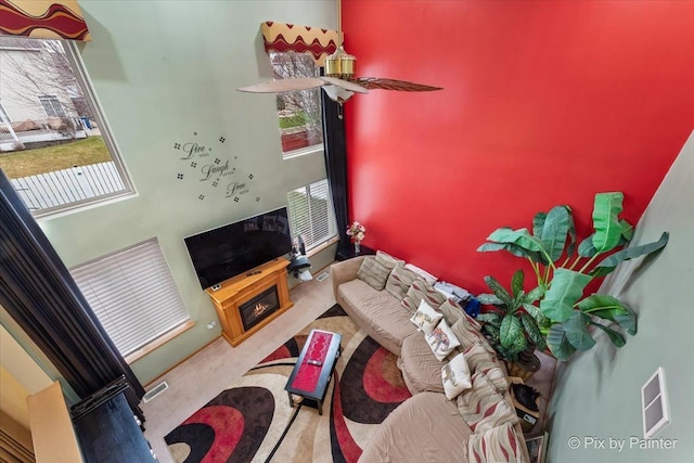 carpeted living room with a fireplace and ceiling fan