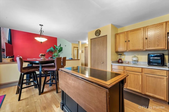 kitchen with decorative light fixtures, a kitchen island, and light hardwood / wood-style flooring