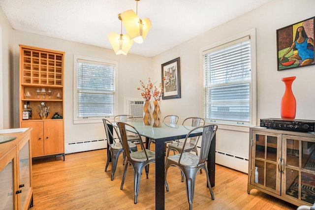 dining space featuring a baseboard heating unit, a wealth of natural light, and light hardwood / wood-style flooring