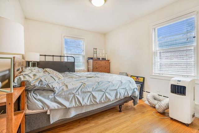 bedroom with wood-type flooring and a baseboard heating unit