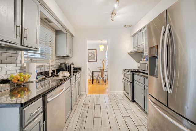 kitchen with decorative backsplash, gray cabinets, light hardwood / wood-style floors, and appliances with stainless steel finishes