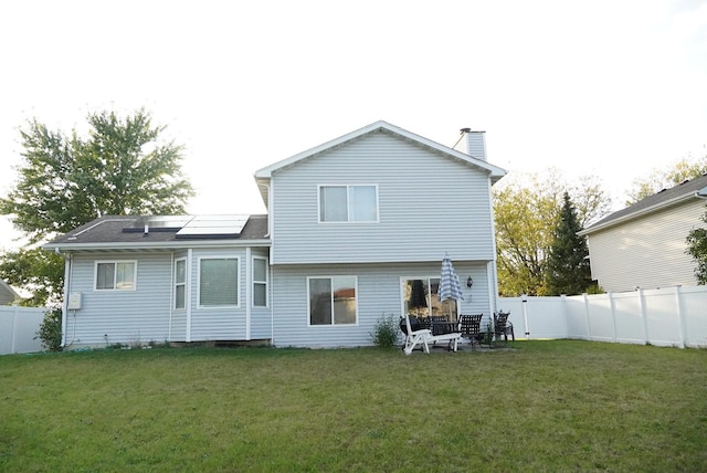 back of house featuring a lawn and solar panels