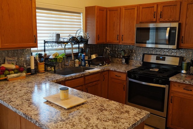 kitchen featuring decorative backsplash, appliances with stainless steel finishes, light stone countertops, and sink