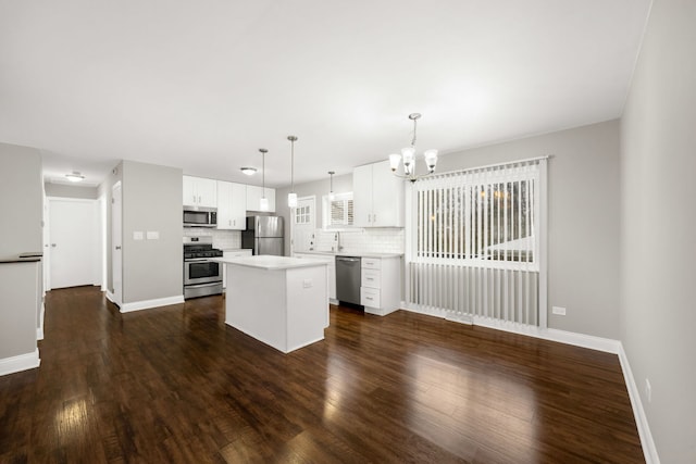 kitchen with tasteful backsplash, stainless steel appliances, dark wood-type flooring, decorative light fixtures, and a center island