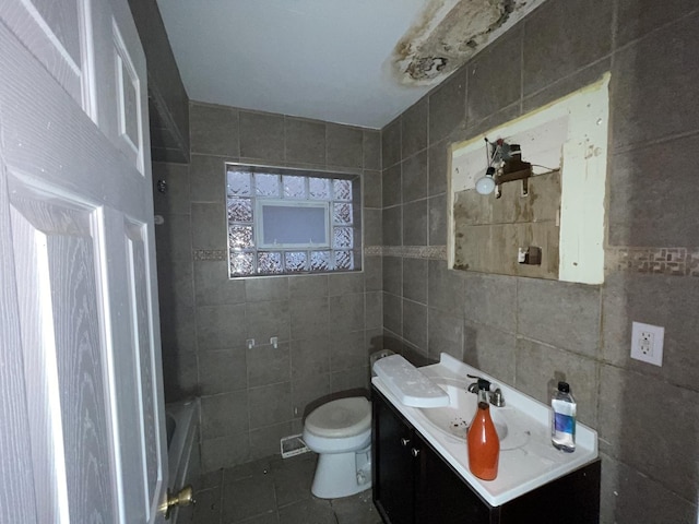 bathroom with vanity, tile patterned floors, a bathing tub, toilet, and tile walls