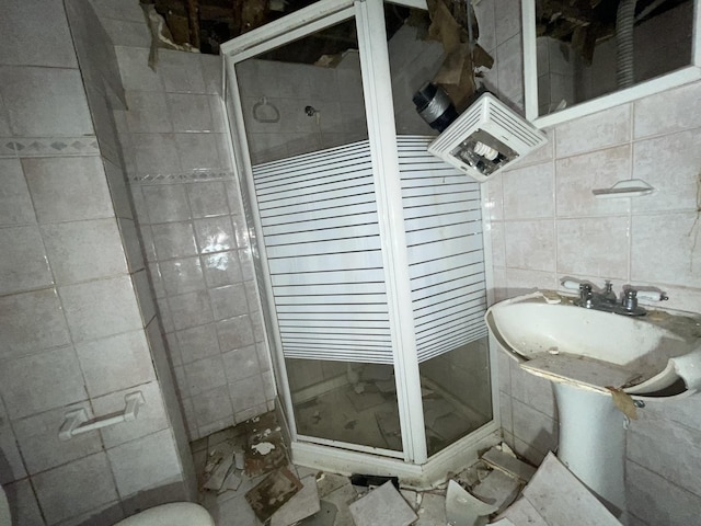 bathroom with a shower with door and tile walls