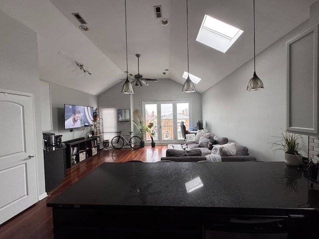 kitchen with white cabinetry, ceiling fan, dark wood-type flooring, decorative light fixtures, and vaulted ceiling with skylight