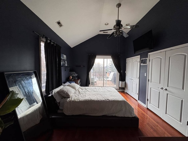 bedroom with ceiling fan, vaulted ceiling, dark wood-type flooring, and two closets