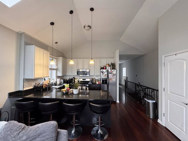 kitchen with tasteful backsplash, kitchen peninsula, hanging light fixtures, and appliances with stainless steel finishes