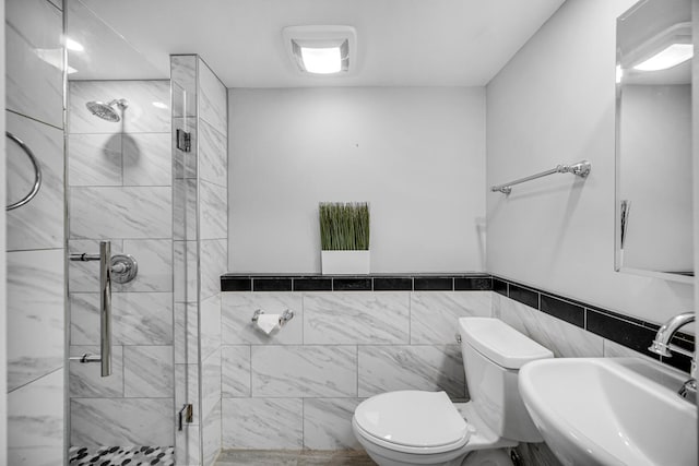 bathroom featuring a shower with door, toilet, tile walls, and sink