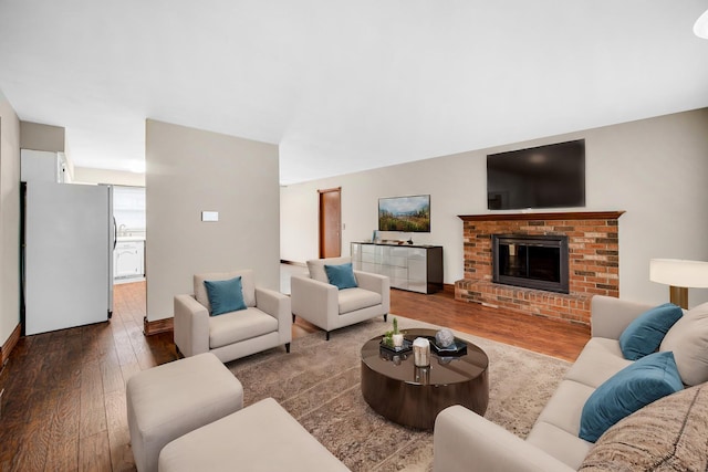 living room featuring dark hardwood / wood-style floors and a brick fireplace