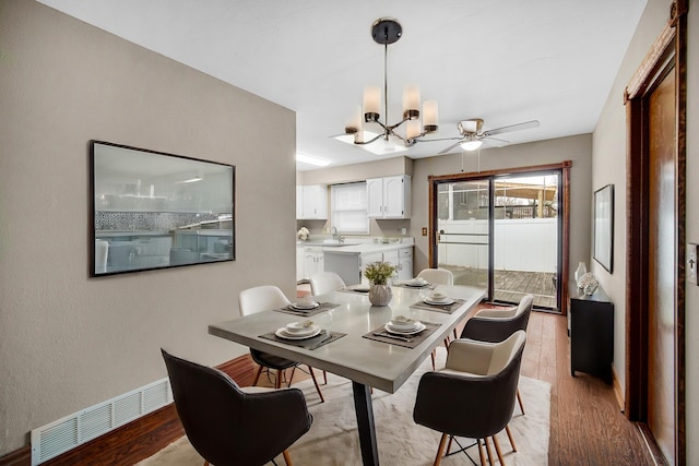 dining room featuring ceiling fan with notable chandelier, light hardwood / wood-style floors, and sink