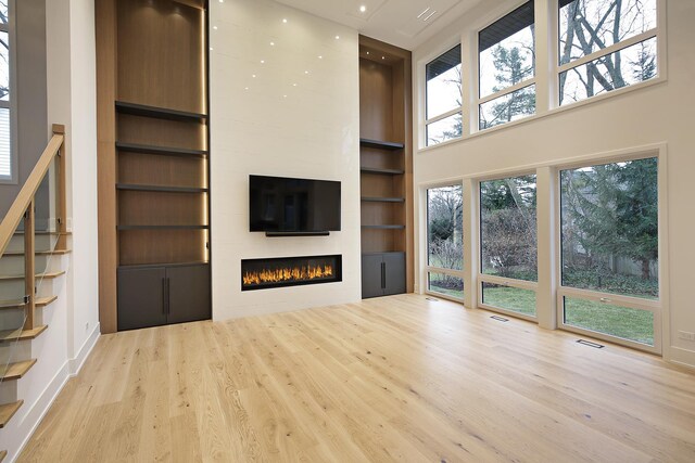 kitchen featuring plenty of natural light, a large fireplace, dark stone counters, and light hardwood / wood-style flooring