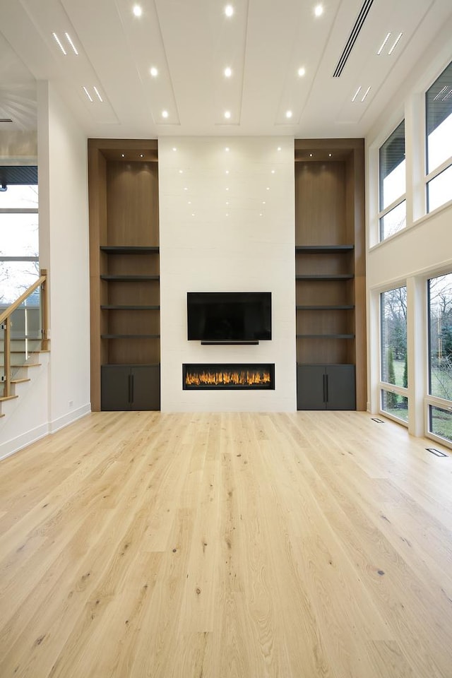 unfurnished living room featuring built in features, recessed lighting, visible vents, a large fireplace, and wood finished floors