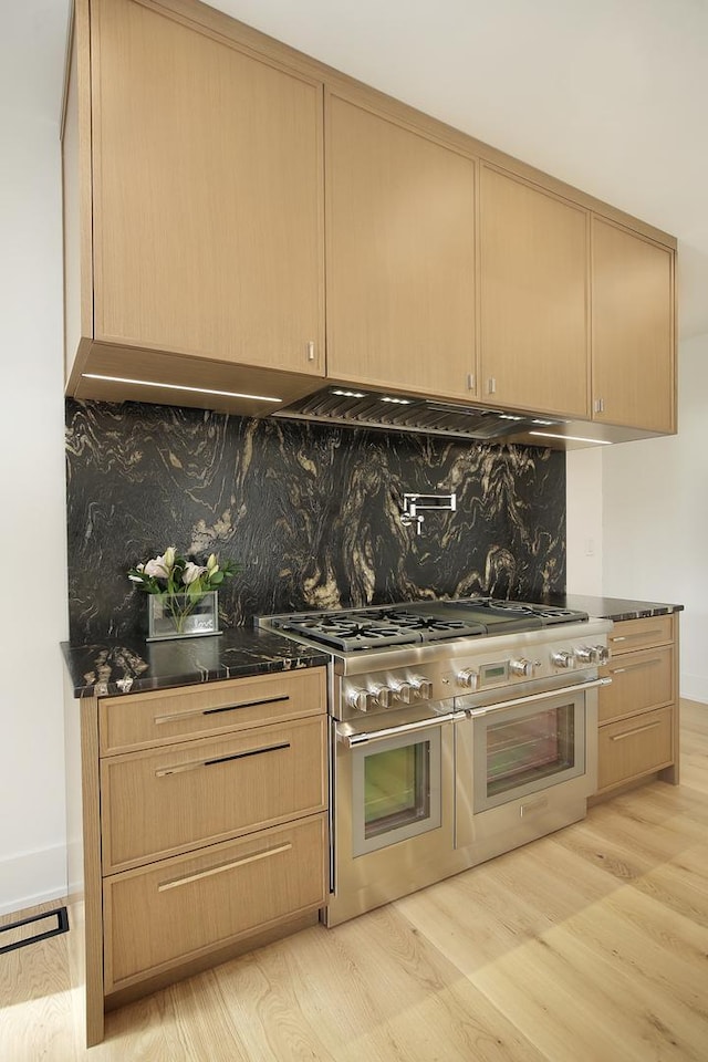 kitchen featuring light brown cabinets, tasteful backsplash, double oven range, and light hardwood / wood-style floors