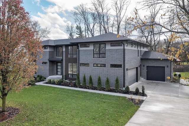 prairie-style home with a front yard, concrete driveway, brick siding, and an attached garage